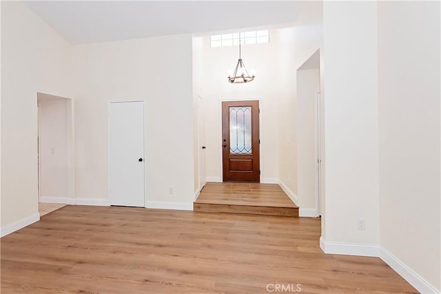 entrance foyer featuring light hardwood / wood-style floors, a high ceiling, and an inviting chandelier