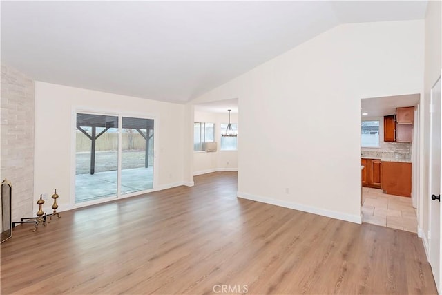 unfurnished living room with light hardwood / wood-style floors, lofted ceiling, and a chandelier