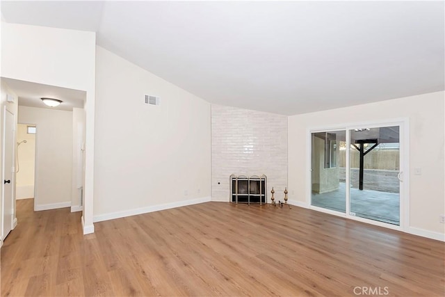 unfurnished living room with light wood-type flooring, a tile fireplace, and vaulted ceiling