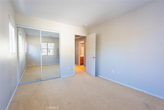 unfurnished bedroom featuring light carpet and a closet