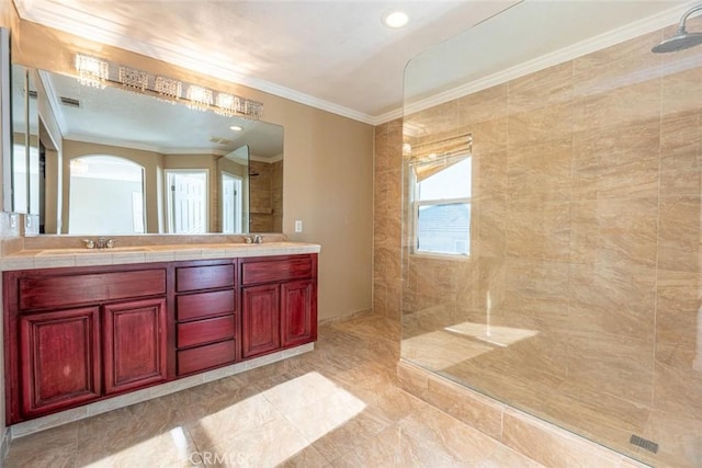 bathroom with a tile shower, vanity, and crown molding