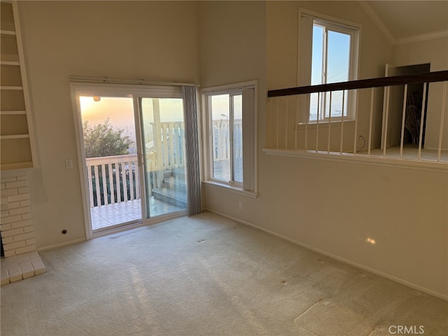 carpeted spare room featuring a fireplace, lofted ceiling, crown molding, and a healthy amount of sunlight