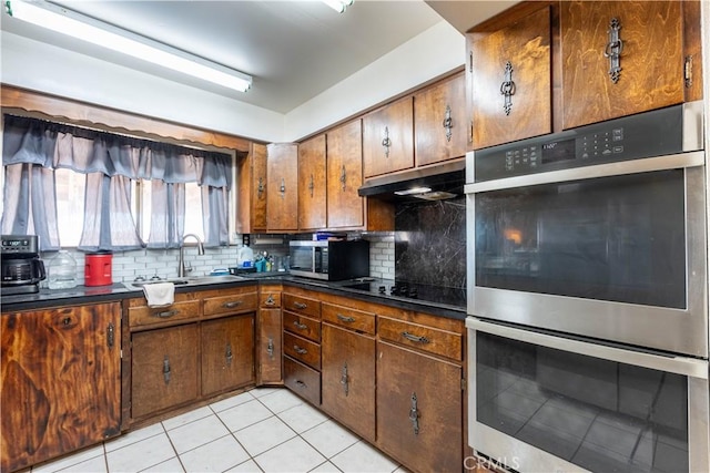 kitchen with stainless steel appliances, light tile patterned floors, sink, and backsplash