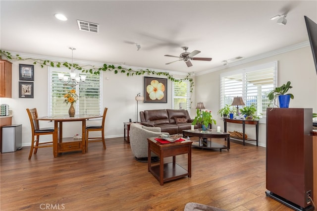 living room featuring ceiling fan with notable chandelier, crown molding, and dark wood-type flooring