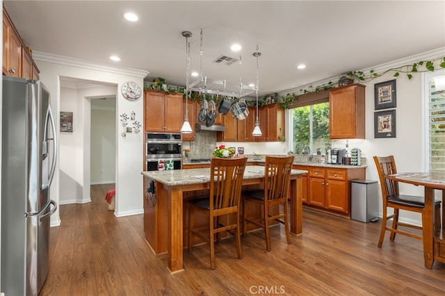 kitchen featuring pendant lighting, stainless steel appliances, a kitchen island, and dark hardwood / wood-style floors