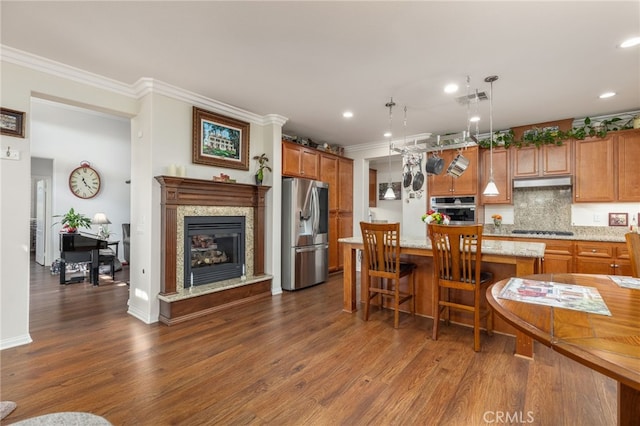 kitchen featuring appliances with stainless steel finishes, a kitchen breakfast bar, dark wood-type flooring, pendant lighting, and a center island