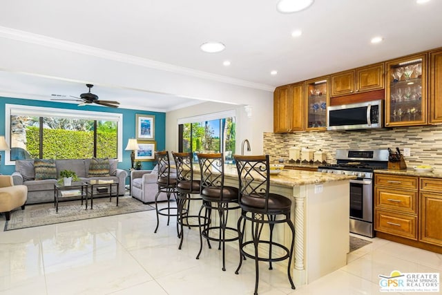 kitchen with a kitchen breakfast bar, stainless steel appliances, light stone counters, and plenty of natural light