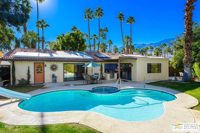 view of swimming pool with a mountain view, a patio, an in ground hot tub, and a water slide