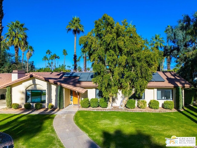 view of front of property featuring solar panels and a front lawn