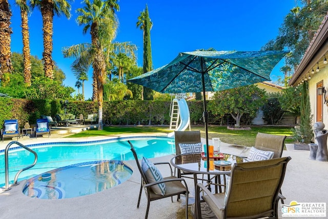 view of swimming pool with a patio area and a water slide