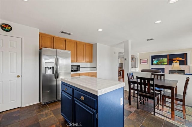 kitchen with tile countertops, stainless steel fridge, and a center island