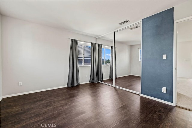 unfurnished bedroom with dark hardwood / wood-style flooring and a closet