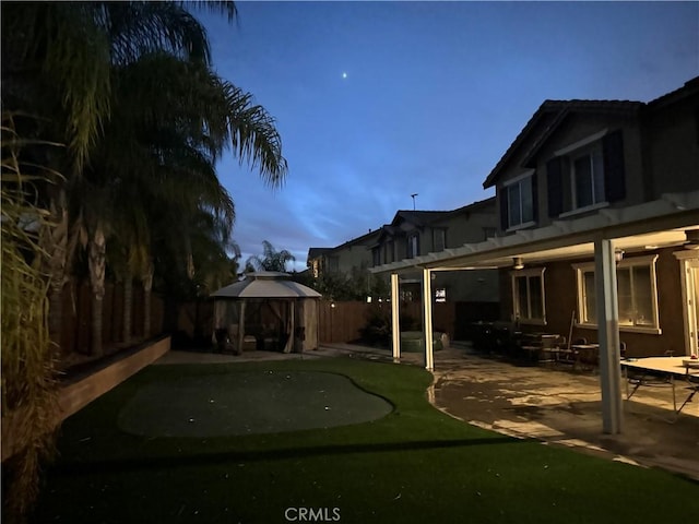 yard at dusk featuring a gazebo and a patio