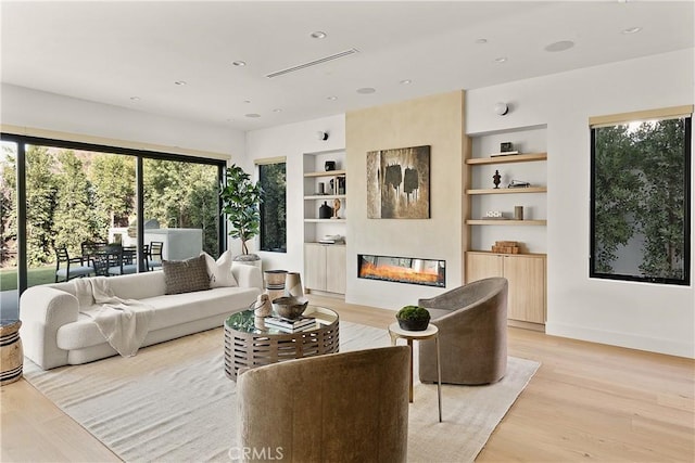 living room with built in shelves and light wood-type flooring