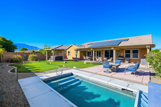 back of house with solar panels, a patio area, a mountain view, and a fenced in pool