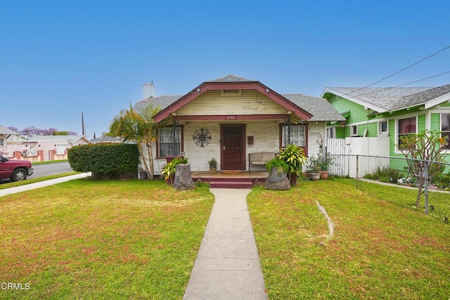 bungalow-style home featuring a porch, a front yard, and fence