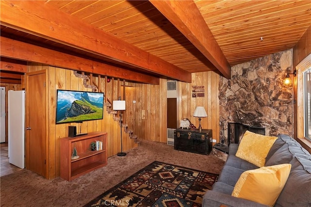 carpeted living room featuring beamed ceiling, wood ceiling, a fireplace, and wooden walls