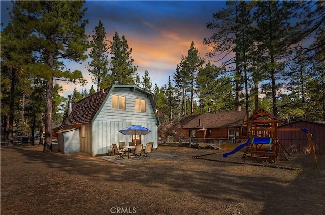 back house at dusk featuring a playground and a garage