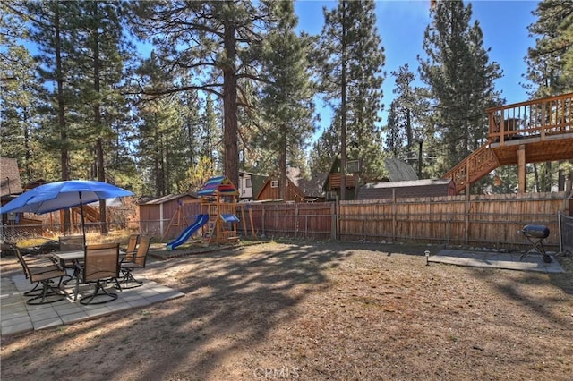 view of yard featuring a deck, a playground, and a patio