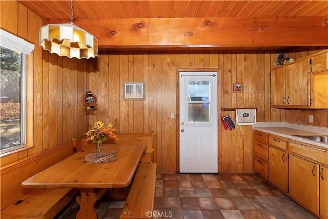 kitchen featuring hanging light fixtures, wooden ceiling, and wood walls