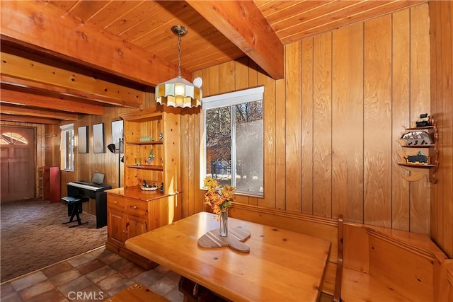 unfurnished dining area featuring beam ceiling, wooden ceiling, dark tile patterned floors, and wooden walls