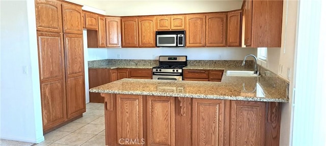 kitchen with stainless steel appliances, light stone countertops, sink, and kitchen peninsula