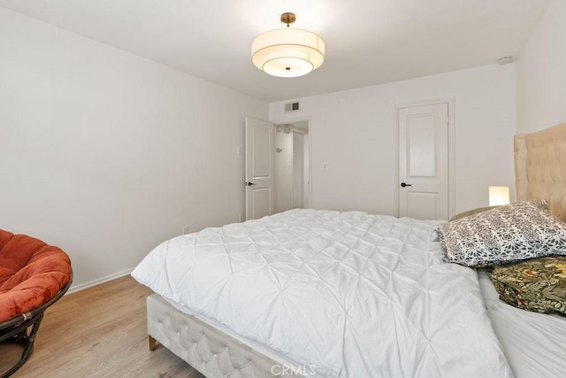 bedroom featuring light wood-type flooring, visible vents, and baseboards