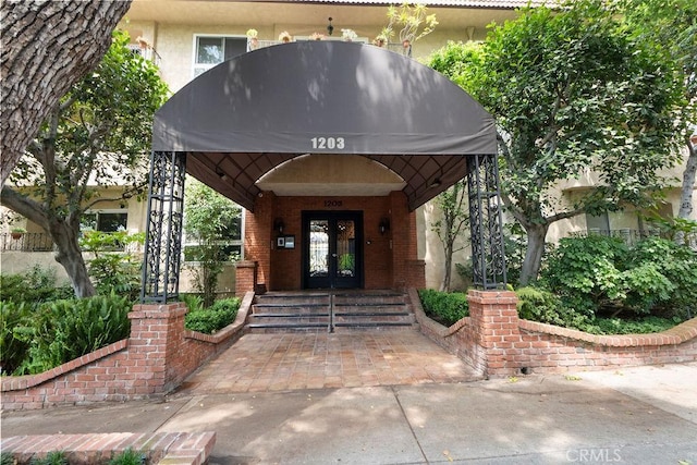 view of exterior entry featuring french doors and brick siding