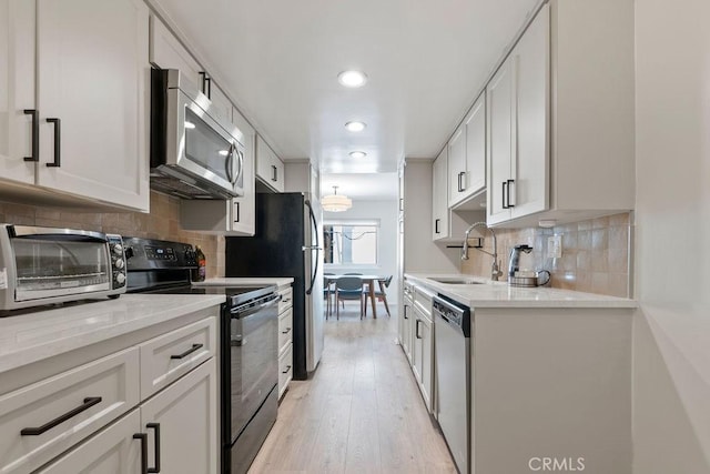 kitchen with a toaster, appliances with stainless steel finishes, a sink, and white cabinets