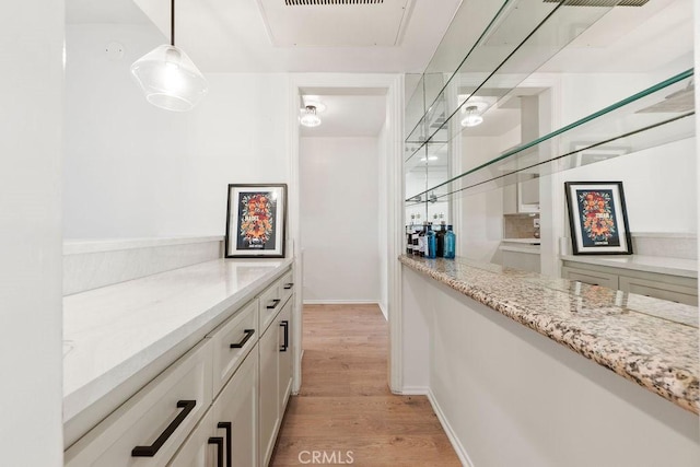 bar with pendant lighting, baseboards, and light wood finished floors