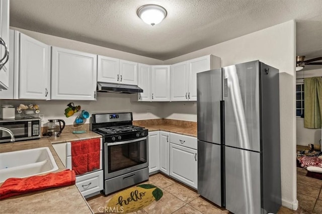 kitchen with appliances with stainless steel finishes, a textured ceiling, ceiling fan, light tile patterned floors, and white cabinets