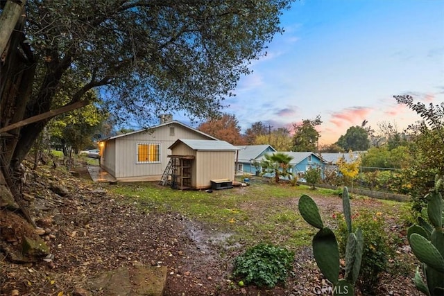 back house at dusk featuring a shed