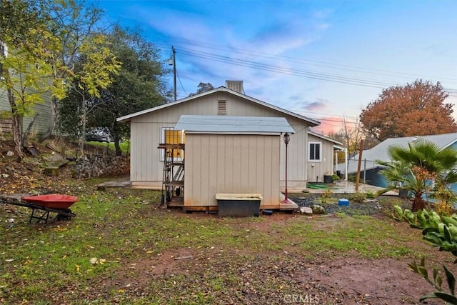 back of house with a storage unit