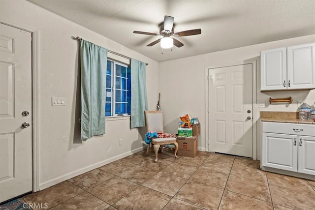 interior space featuring white cabinets, ceiling fan, and light tile patterned flooring