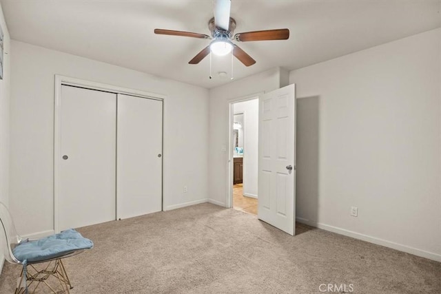 unfurnished bedroom with ceiling fan, light carpet, and a closet