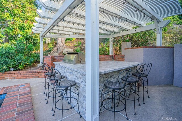 view of patio with area for grilling, a pergola, and exterior bar