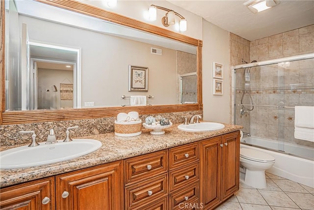 full bathroom featuring vanity, tile patterned flooring, bath / shower combo with glass door, and toilet