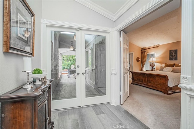 doorway to outside with light wood-type flooring, lofted ceiling, french doors, and crown molding