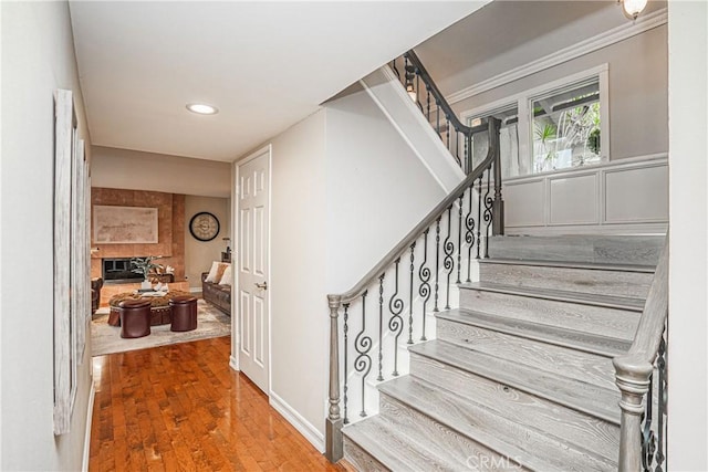 stairs with recessed lighting, a tiled fireplace, and wood finished floors