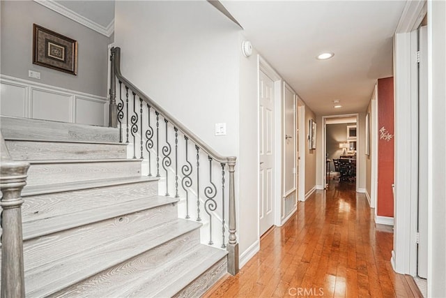 stairs featuring baseboards, ornamental molding, wood-type flooring, and recessed lighting