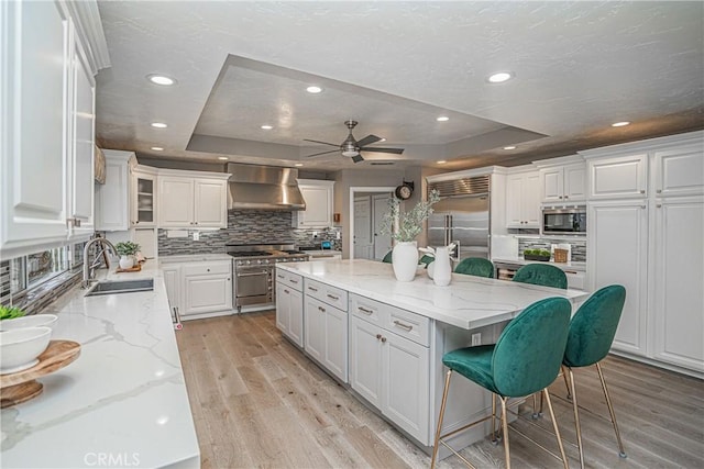 kitchen with white cabinets, a kitchen island, ventilation hood, and built in appliances