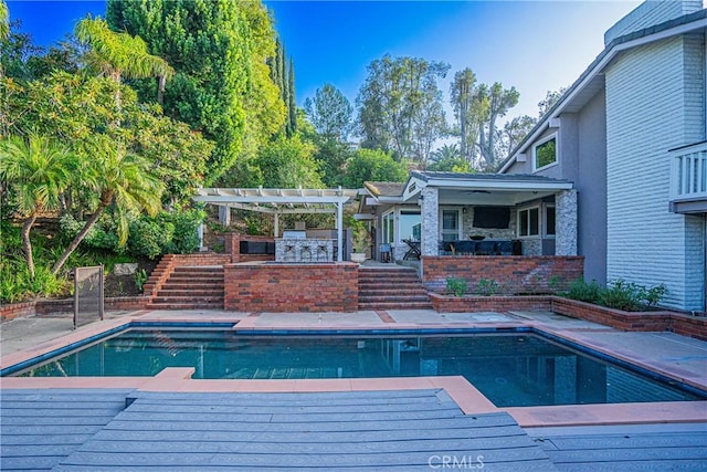 view of swimming pool with exterior kitchen, a pergola, an outdoor bar, and a patio