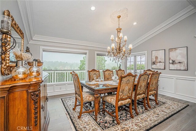 dining room featuring ornamental molding, lofted ceiling, hardwood / wood-style floors, and an inviting chandelier