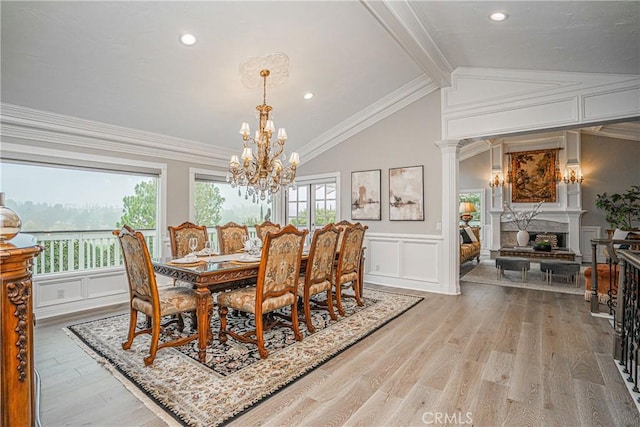 dining area featuring ornamental molding, a chandelier, light wood-type flooring, and vaulted ceiling with beams