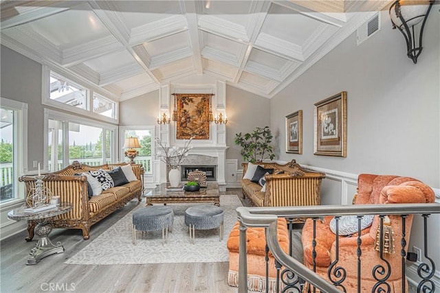 living room featuring a wainscoted wall, visible vents, a glass covered fireplace, light wood-type flooring, and coffered ceiling