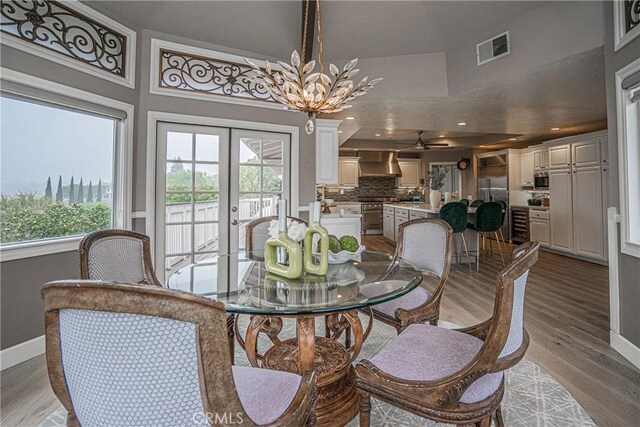 dining area featuring french doors, a chandelier, and light hardwood / wood-style flooring