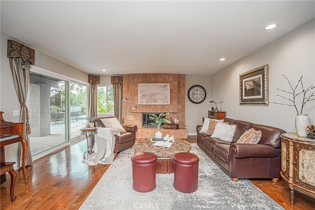 living room with a tiled fireplace, wood finished floors, and recessed lighting