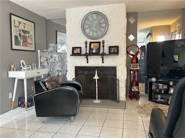 tiled living room featuring a textured ceiling and a stone fireplace