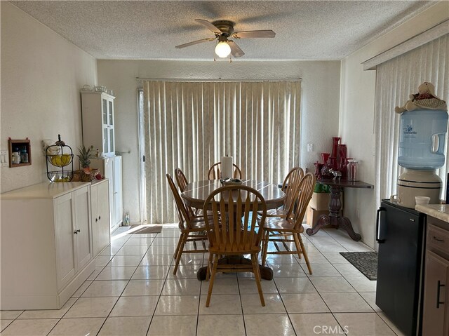 dining space featuring ceiling fan, light tile patterned floors, and a textured ceiling