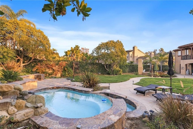 view of pool with a patio area, a yard, and an in ground hot tub